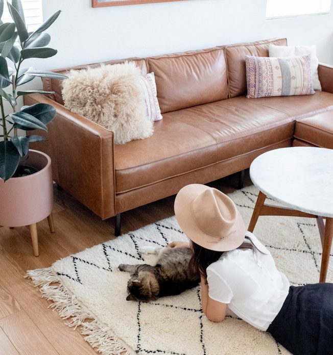 A young woman and her cat lying on the floor of a modern living room